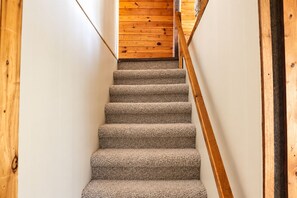 A carpeted staircase with wooden handrails, leading to a wooden floor.