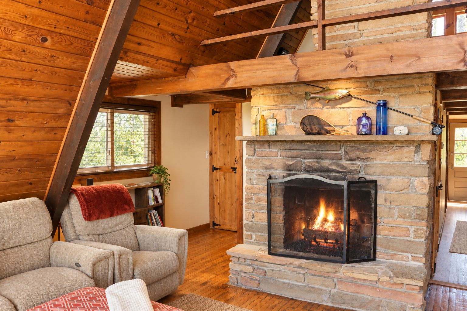 A cozy living room with a stone fireplace, wooden beams, and a comfortable sofa.