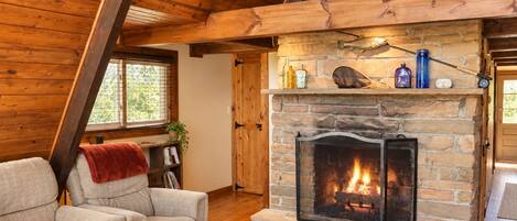 A cozy living room with a stone fireplace, wooden beams, and a comfortable sofa.
