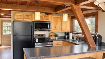 Una cocina con gabinetes de madera, un refrigerador negro, un microondas, una estufa y una encimera de granito.
