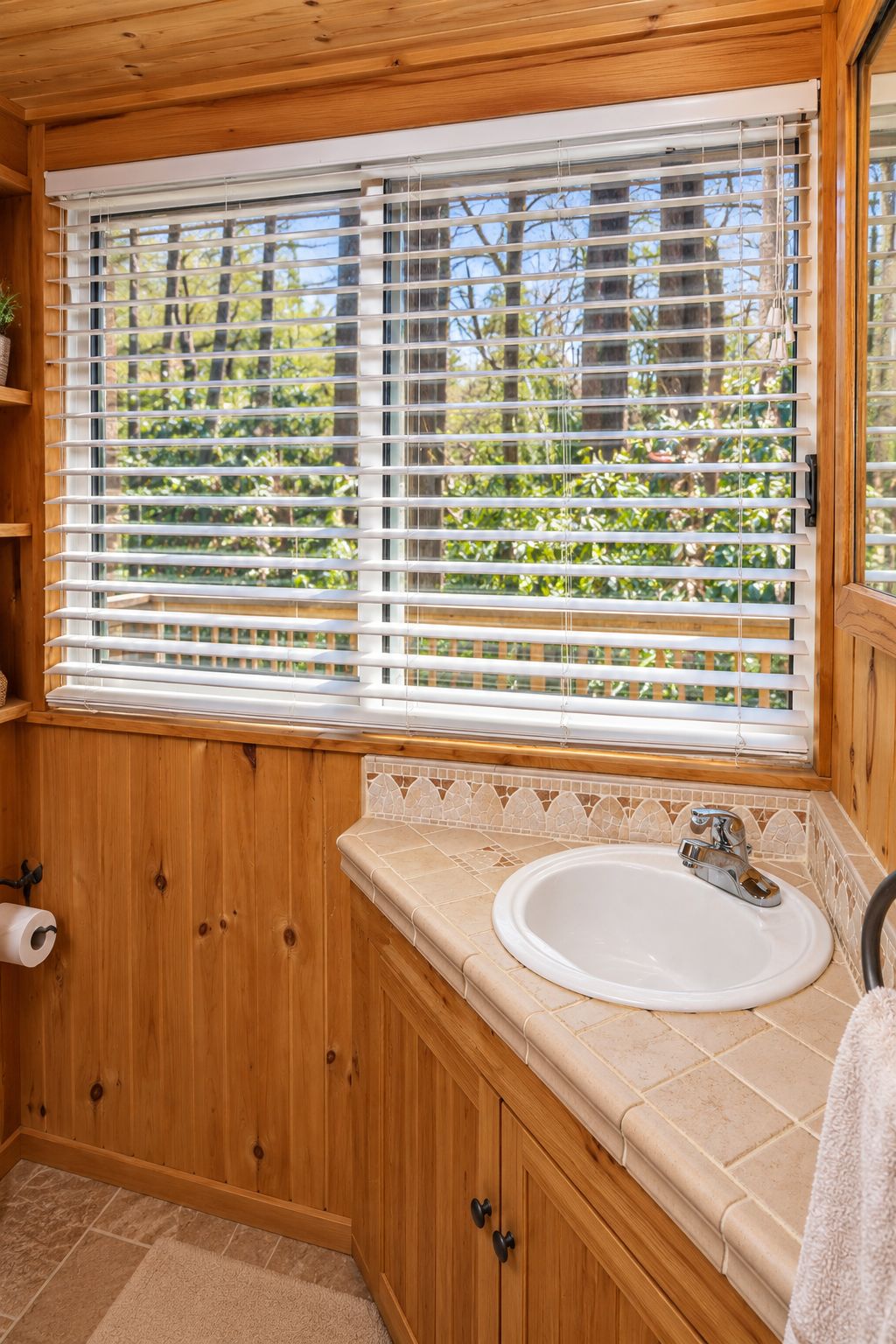 Un bagno in legno con finestra, un lavandino e un water.