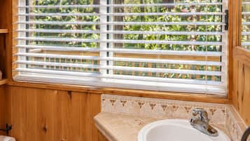 Un bagno in legno con finestra, un lavandino e un water.