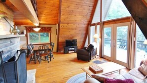Un intérieur de chalet chaleureux avec un coin repas, un canapé et une cheminée.