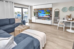 A modern living room with a large TV, a sofa, a coffee table, and a dining area. - Key Largo Ocean Shore Villa 1 with pool & boat slip (Key Largo)
