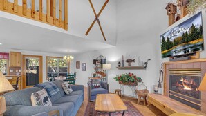 Uma sala de estar acolhedora com lareira, televisão e área de jantar com mobiliário de madeira.