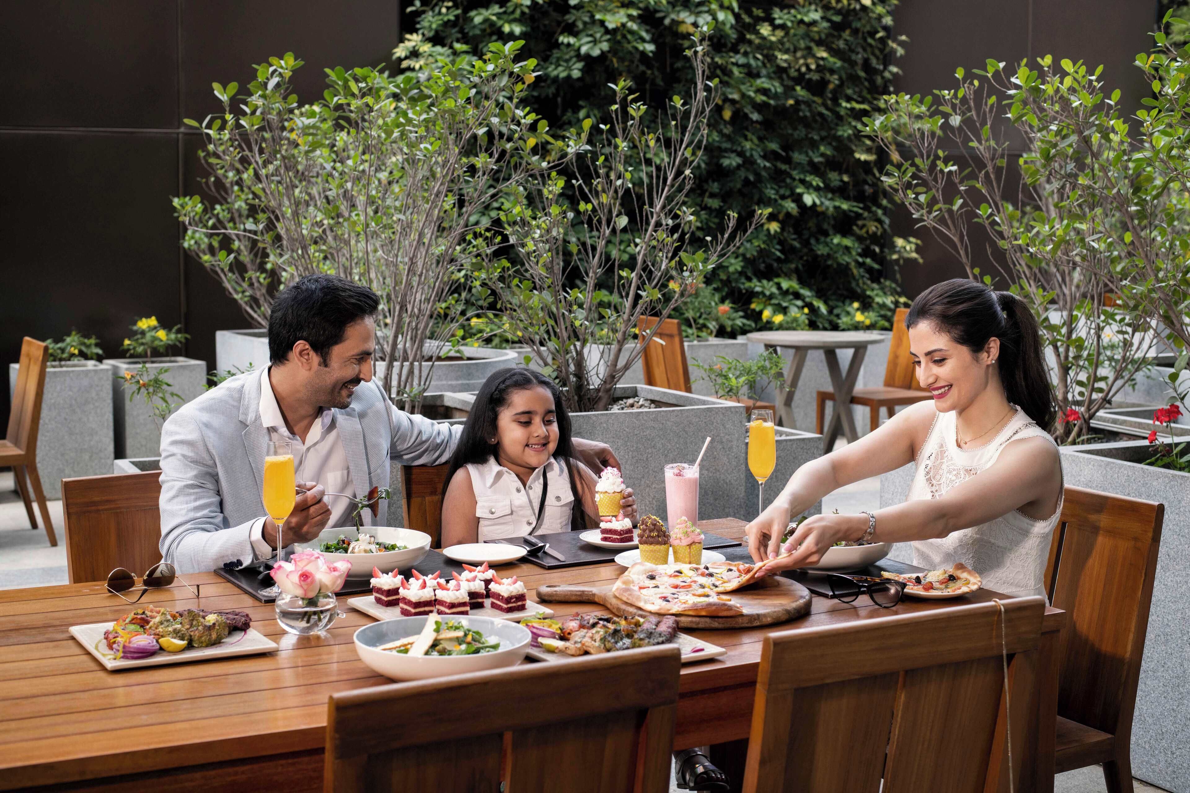 A group of people dining at an outdoor restaurant with various dishes and drinks on the table.