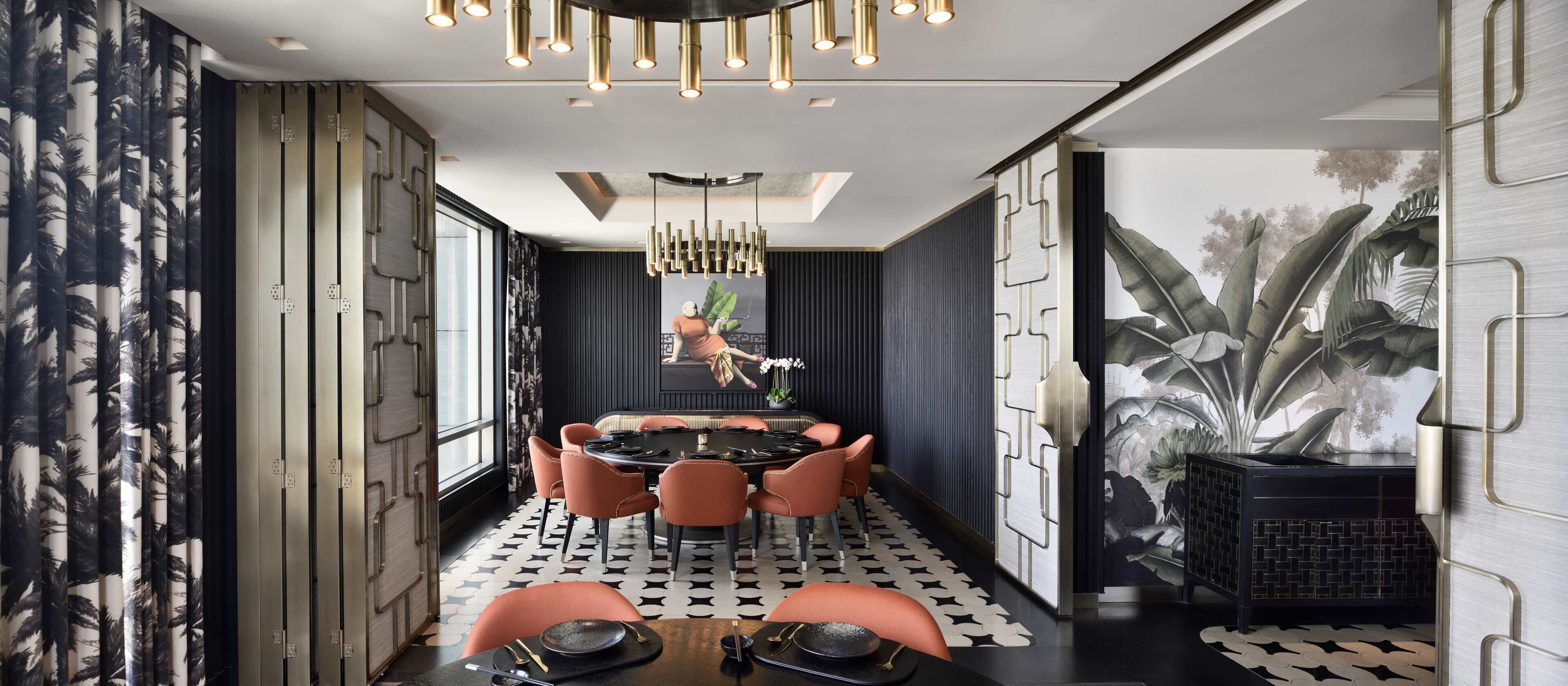 A modern dining area with a round table, orange chairs, and a chandelier.