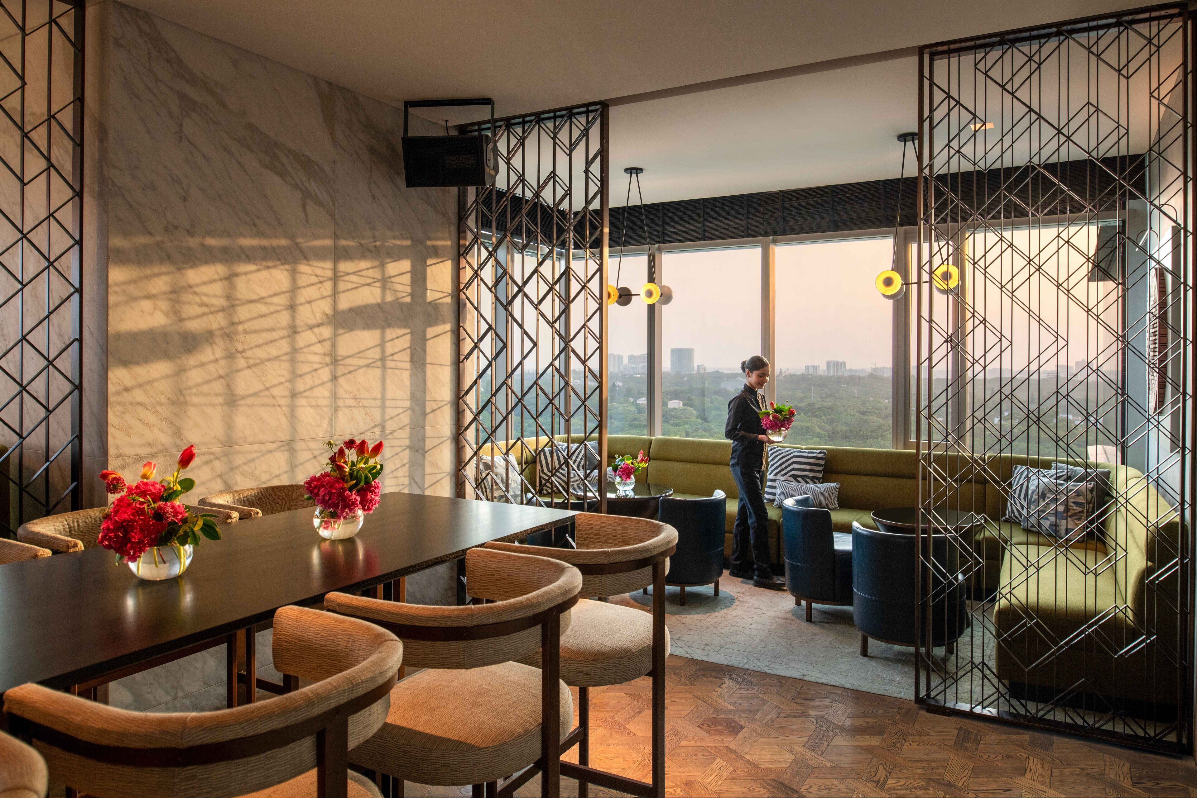A modern interior with a dining area, a sofa, and a view of the city.