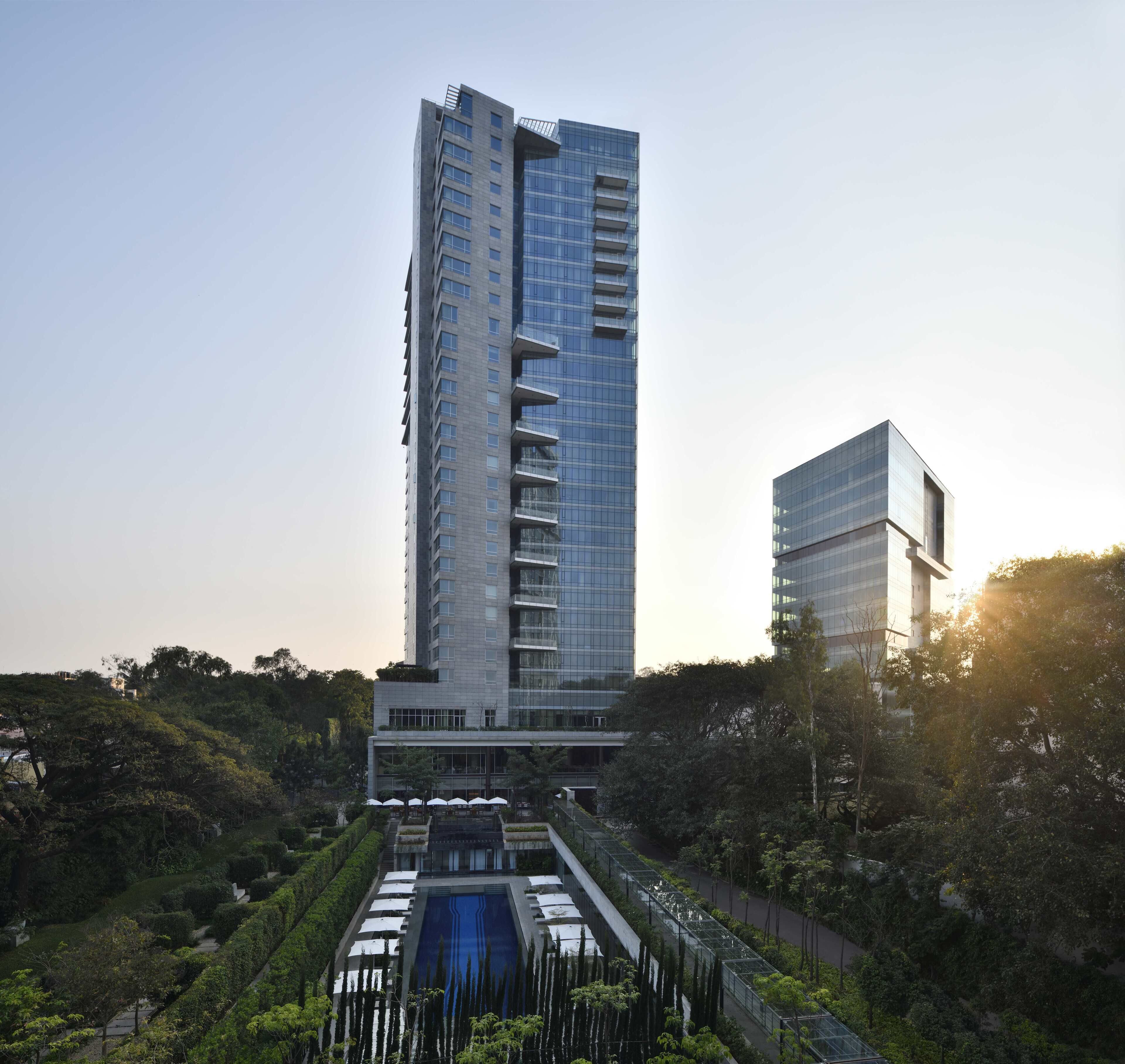A modern high-rise building with a central courtyard featuring a water feature and surrounded by greenery.