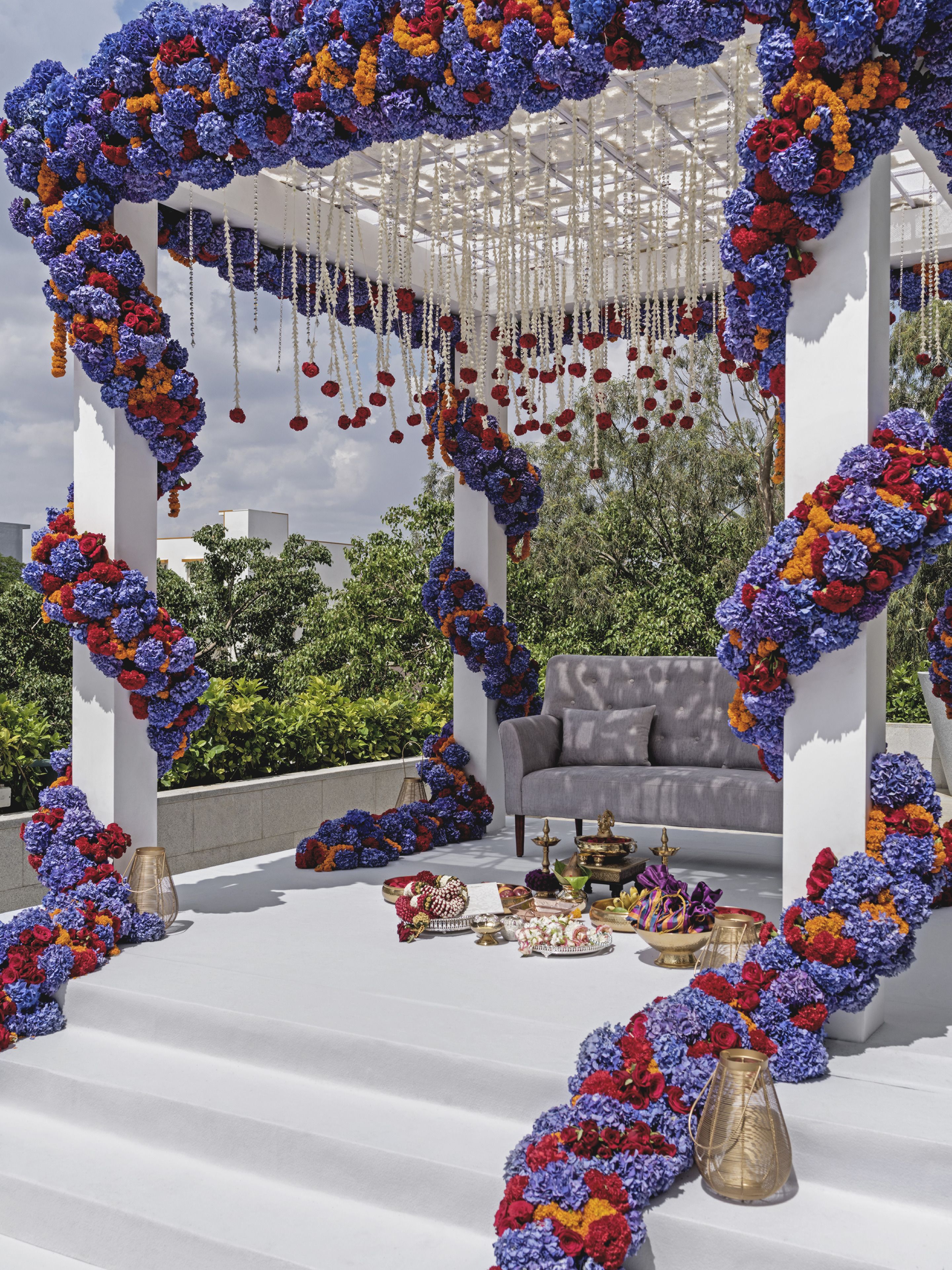 A rooftop setting with a white gazebo adorned with floral arrangements and hanging decorations.