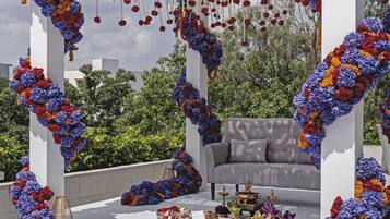 A rooftop setting with a white gazebo adorned with floral arrangements and hanging decorations.