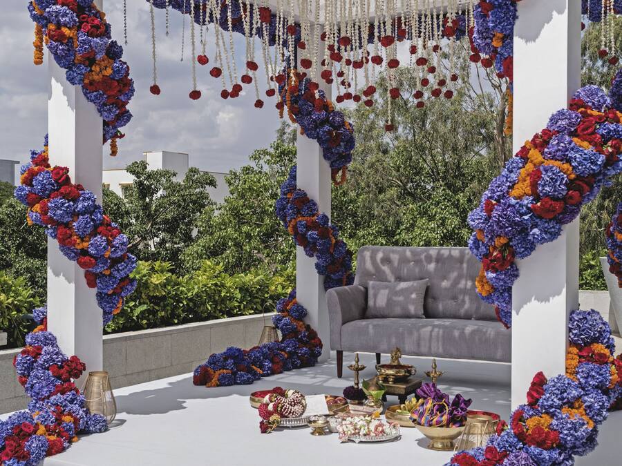 A rooftop setting with a white gazebo adorned with floral arrangements and hanging decorations.