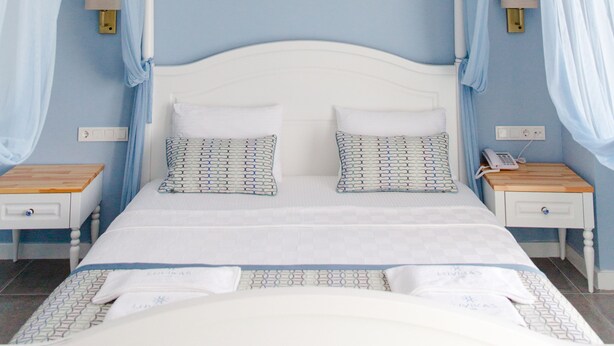 A bedroom with a canopy bed, bedside tables, and a ceiling-mounted smoke detector. - Luvi Kaş Otel - Adults Only (Kas)