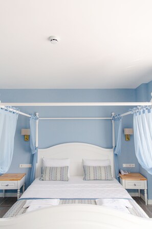 Een slaapkamer met een hemelbed, nachtkastjes en een rookmelder aan het plafond.