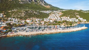 A coastal town with a marina, buildings along the shore, and a rocky hillside in the background. - Luvi Kaş Otel - Adults Only (Kas)