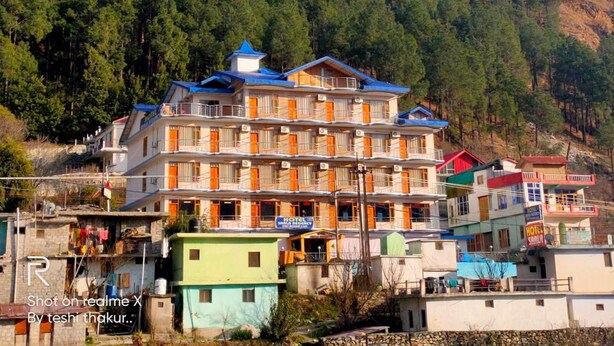 A multi-story hotel with balconies, surrounded by a mountainous landscape. - Hotel Sarla Regency (Bhuntar)