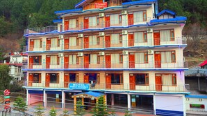 A multi-story hotel with balconies, air conditioning units, and a sign indicating it is a family restaurant and cafe. - Hotel Sarla Regency (Bhuntar)