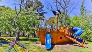 A pirate-themed playground with a slide and a climbing structure. - Cottages at the Even'tide Resort (Wellfleet)