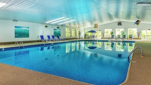 An indoor swimming pool with clear blue water, lounge chairs, and potted plants. - Cottages at the Even'tide Resort (Wellfleet)