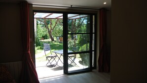 Una habitación con puerta corrediza de vidrio que da a un patio con mesa y sillas.