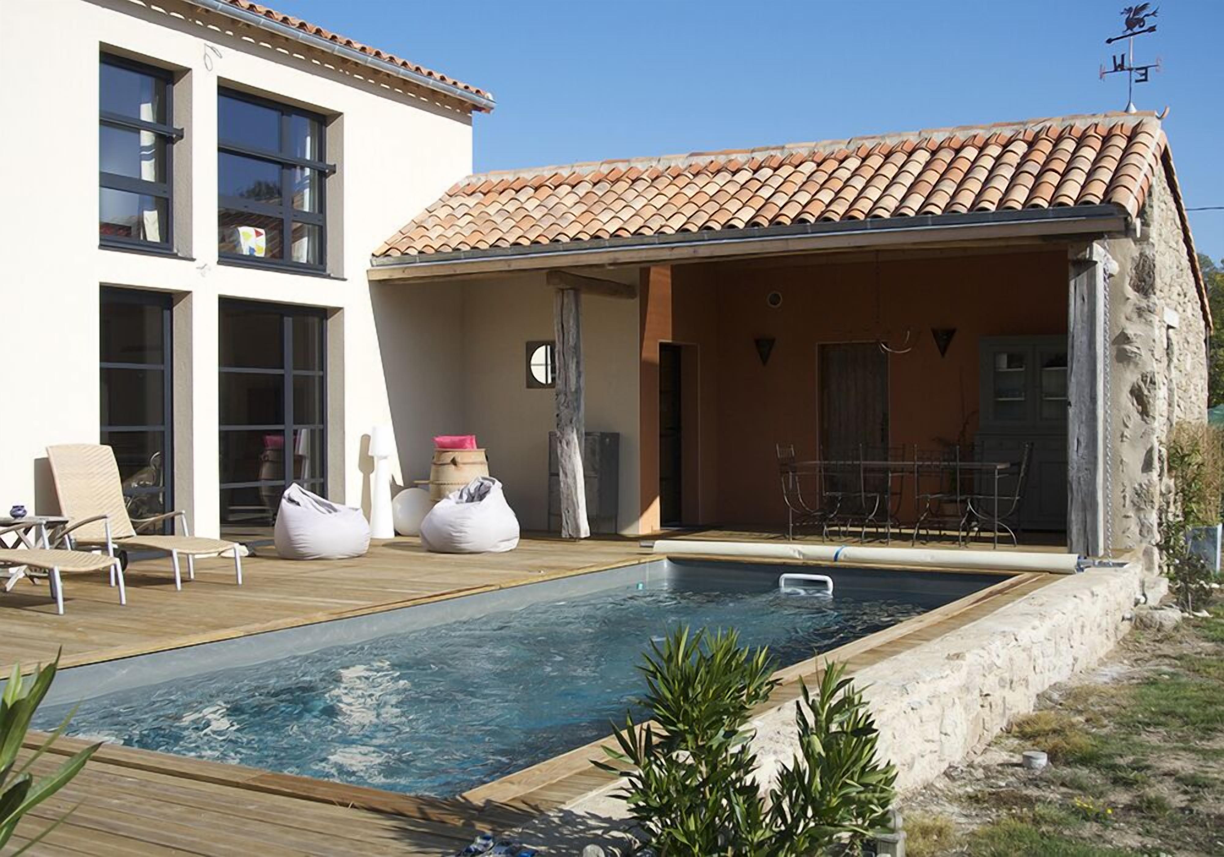 A modern house with a swimming pool, outdoor seating, and a stone exterior.
