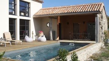 A modern house with a swimming pool, outdoor seating, and a stone exterior.