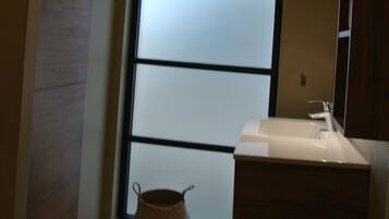 A modern bathroom with a large frosted glass window, a wooden vanity, and a small woven basket on the floor.
