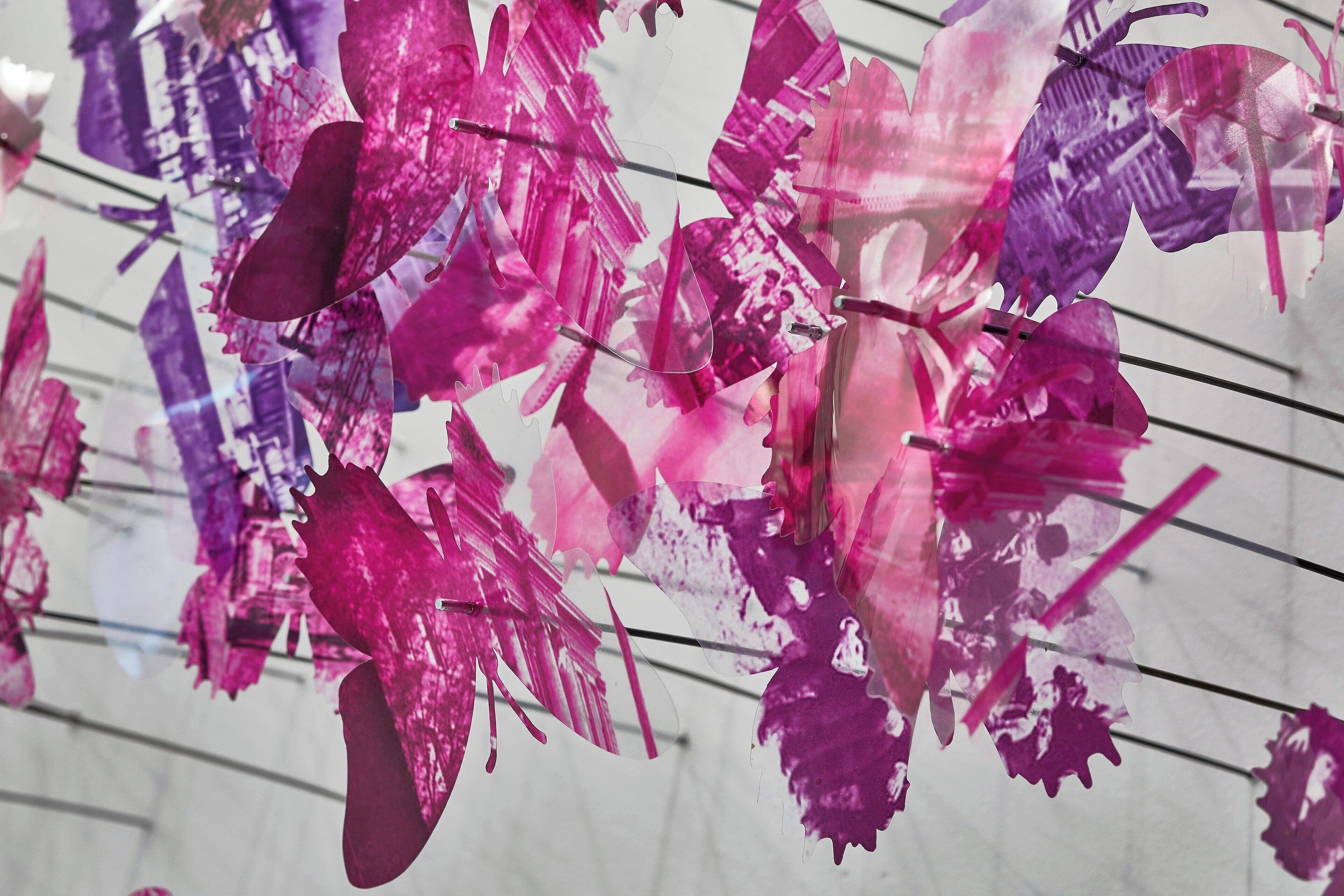 A display of pink and purple paper cutouts hanging from wires.