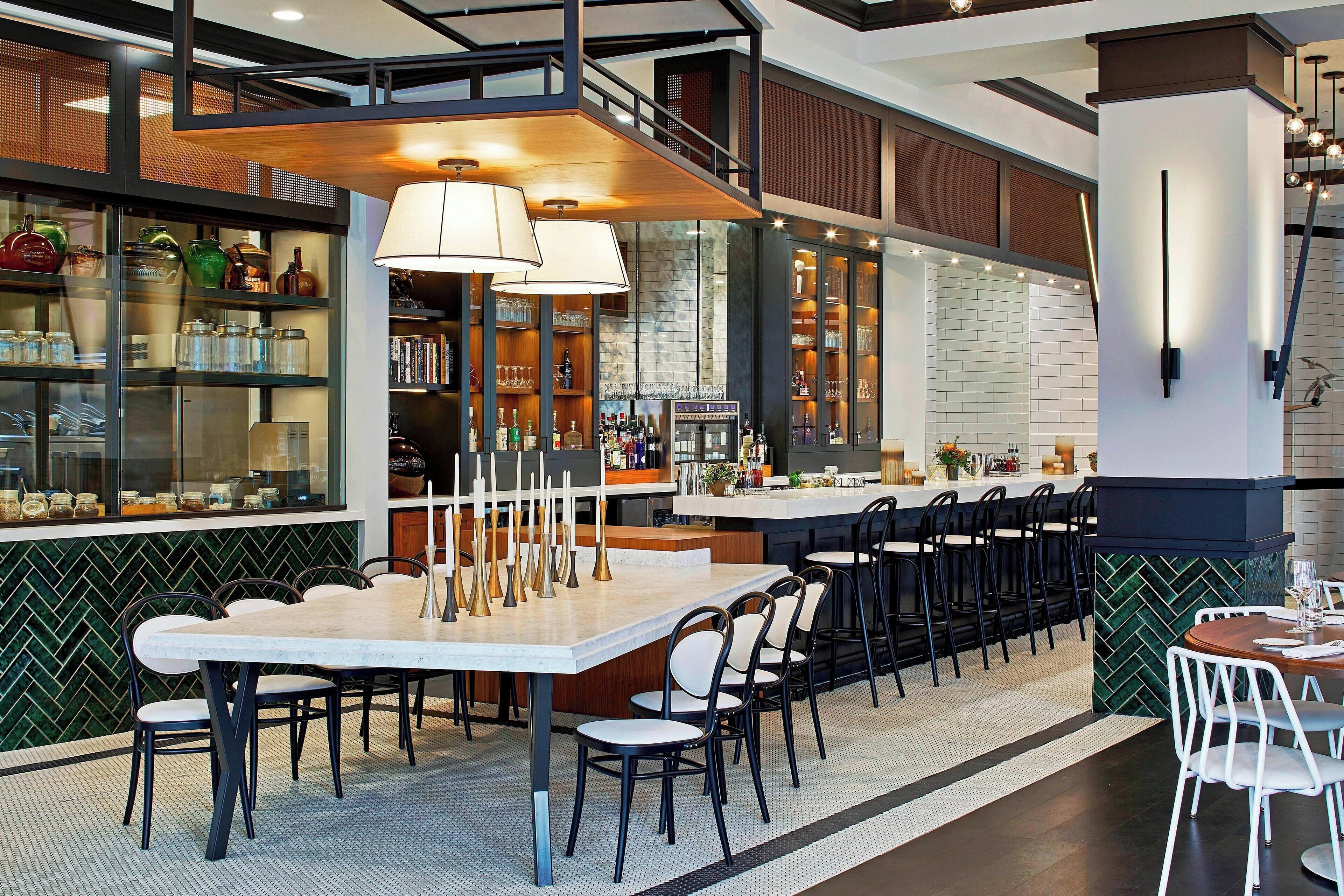 A modern restaurant with a bar area, high ceilings, and a mix of seating options.