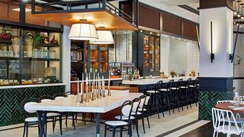 A modern restaurant with a bar area, high ceilings, and a mix of seating options.