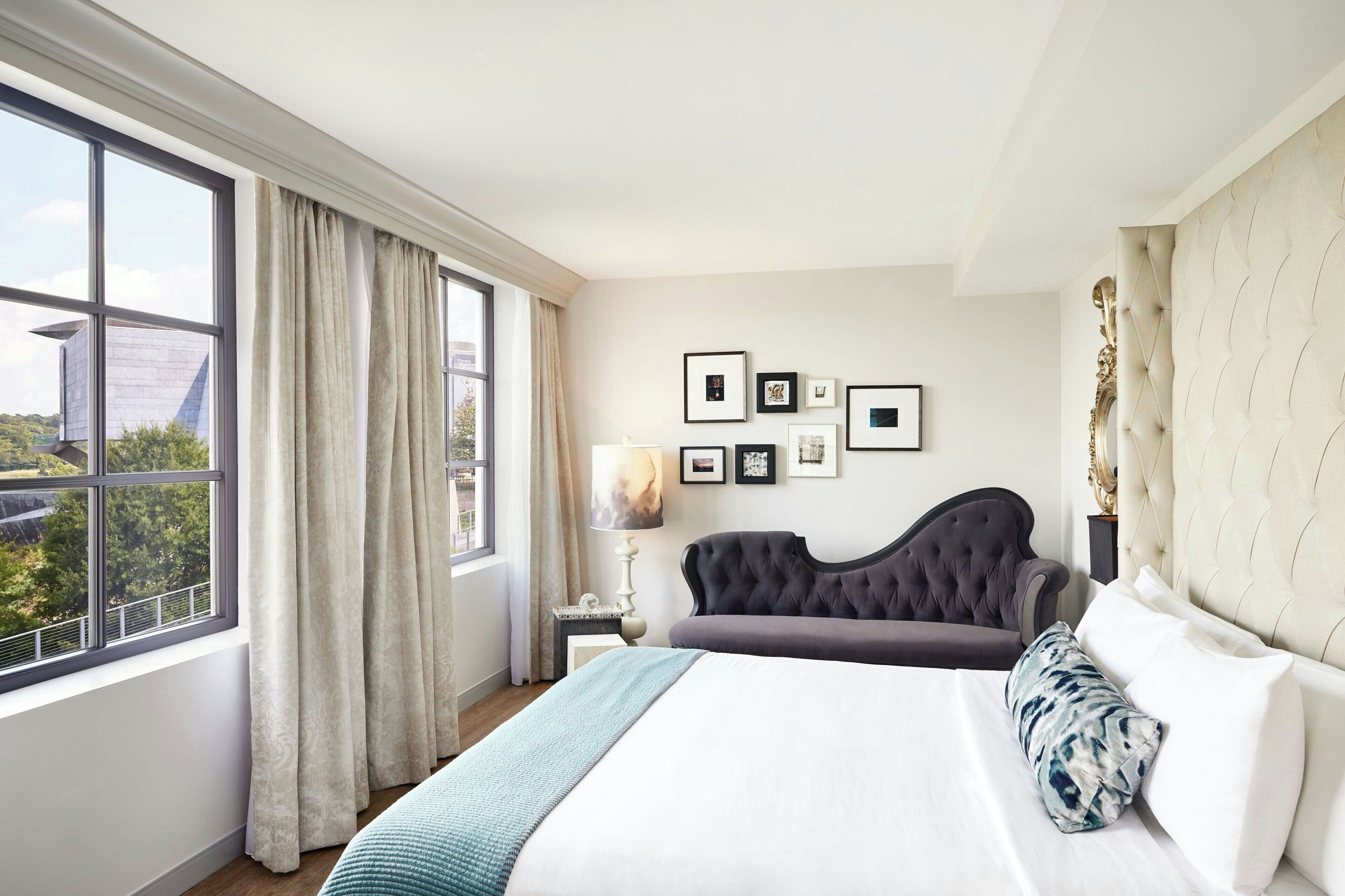 Une chambre d’hôtel avec un grand lit, une table de chevet, une lampe et une fenêtre avec des rideaux.