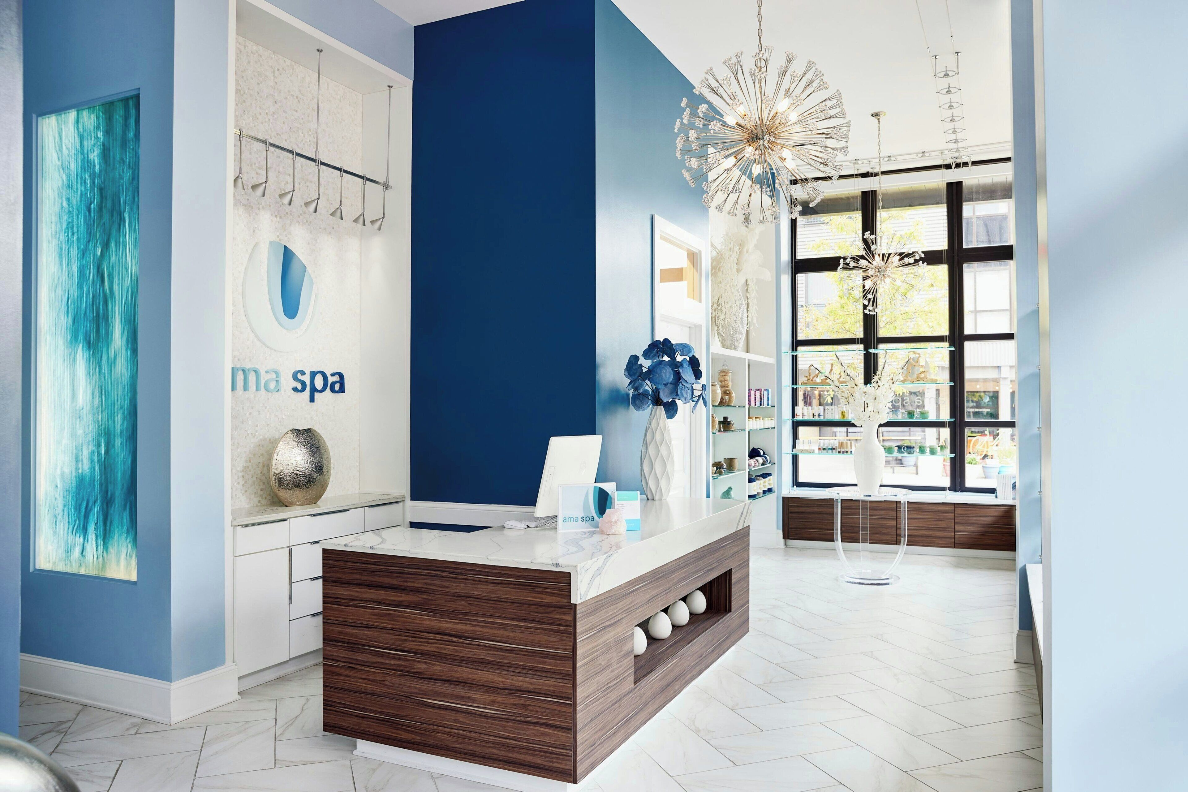 A spa reception area with a modern design, a large window, and a decorative chandelier.