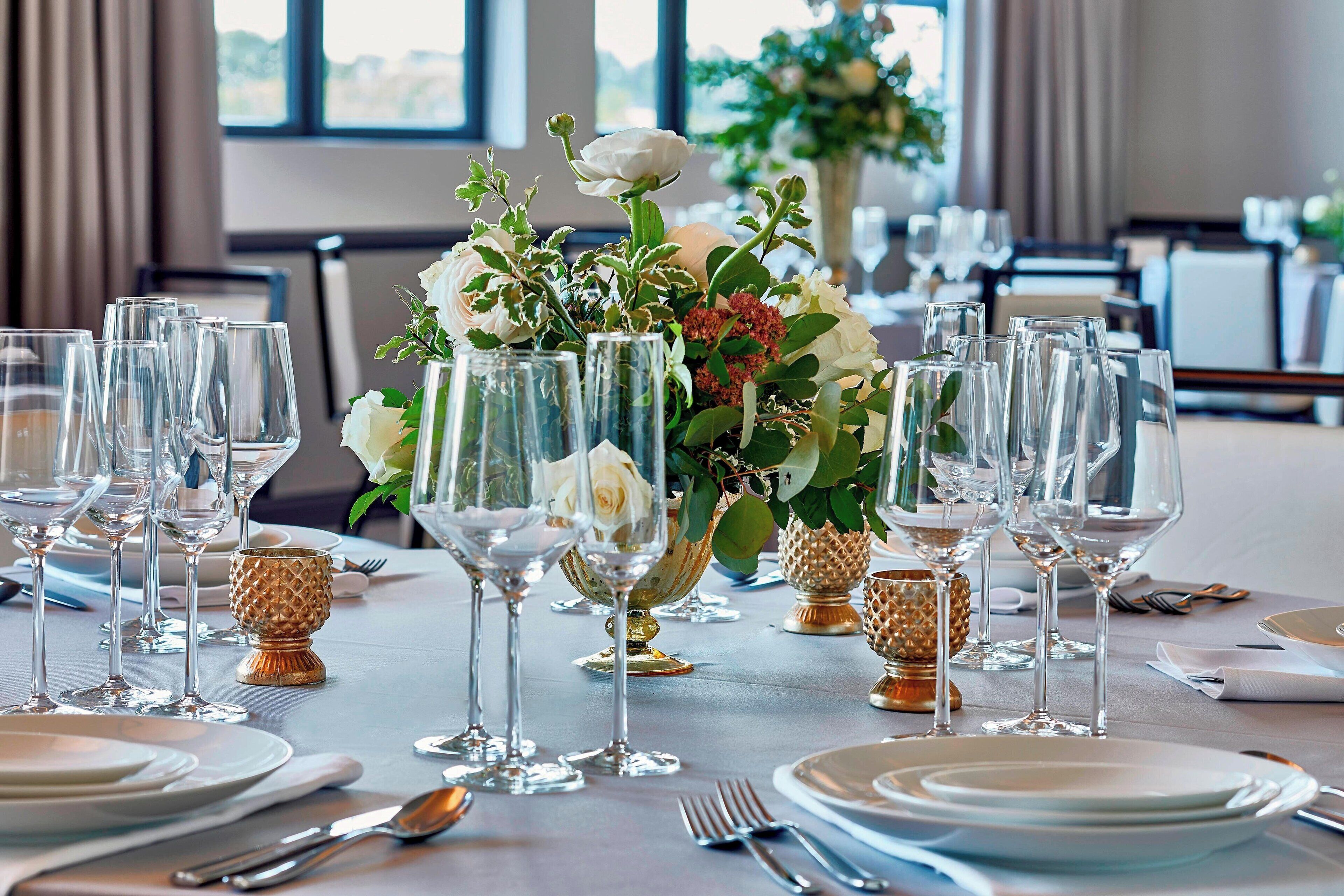 A table set for a formal dining event with multiple wine glasses, plates, and cutlery.