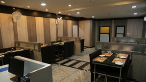 Un hall d’hôtel moderne doté d’un espace salon central, de postes de travail individuels et d’un comptoir d’accueil.