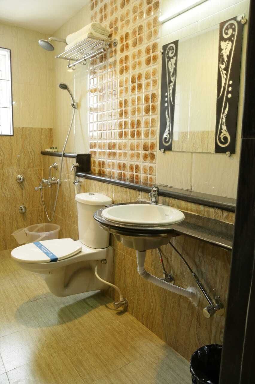 A bathroom with a toilet, sink, shower, and tiled walls.
