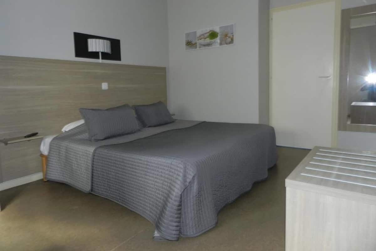 Une chambre à coucher avec un lit, une table de chevet, une lampe et une porte.