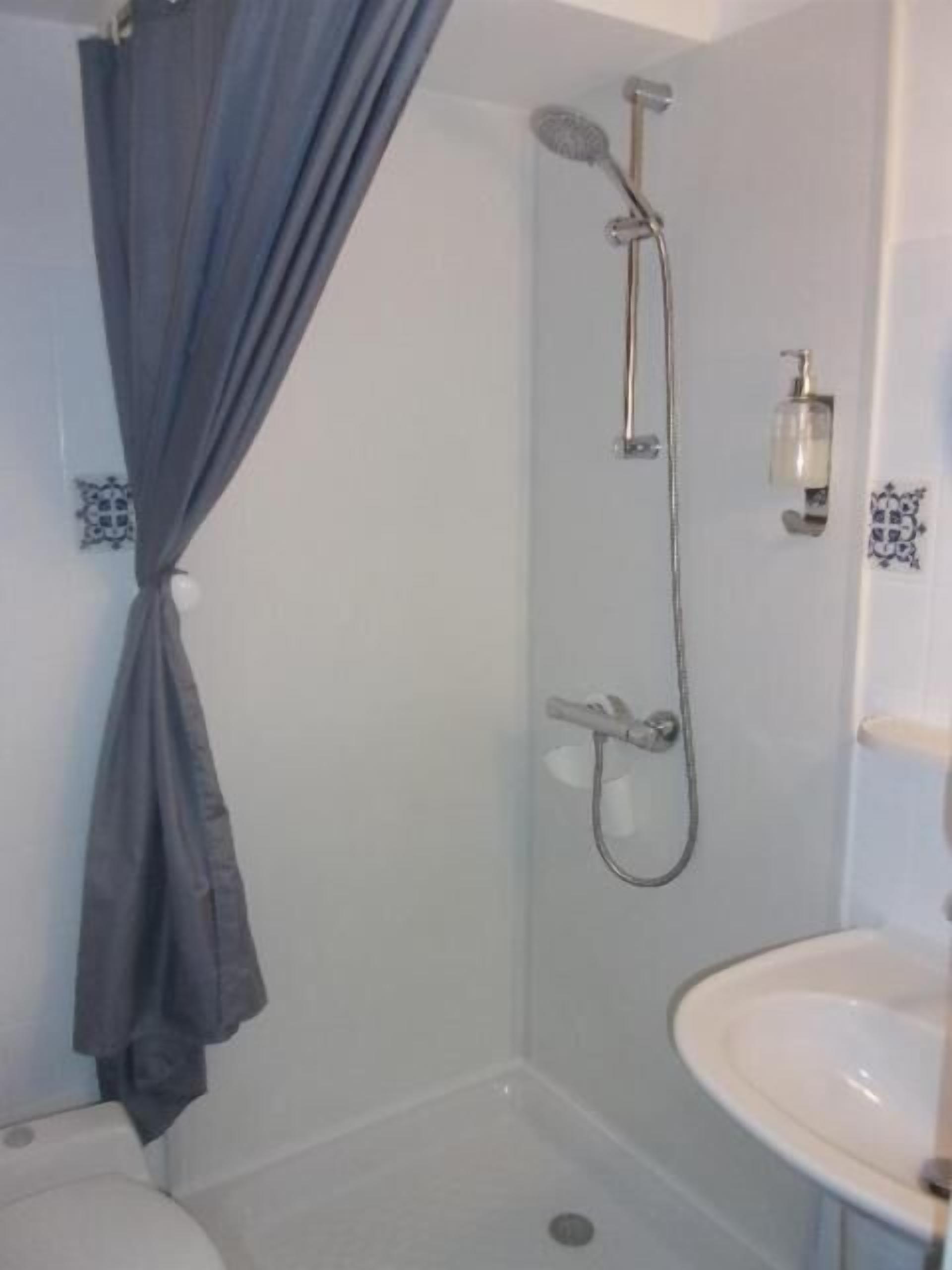 A bathroom with a shower, a sink, and a curtain.