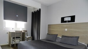 Un dormitorio con cama, escritorio y silla.