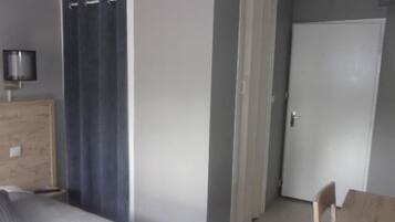 A bedroom with a bed, a wooden nightstand, a lamp, a door, and a chair.