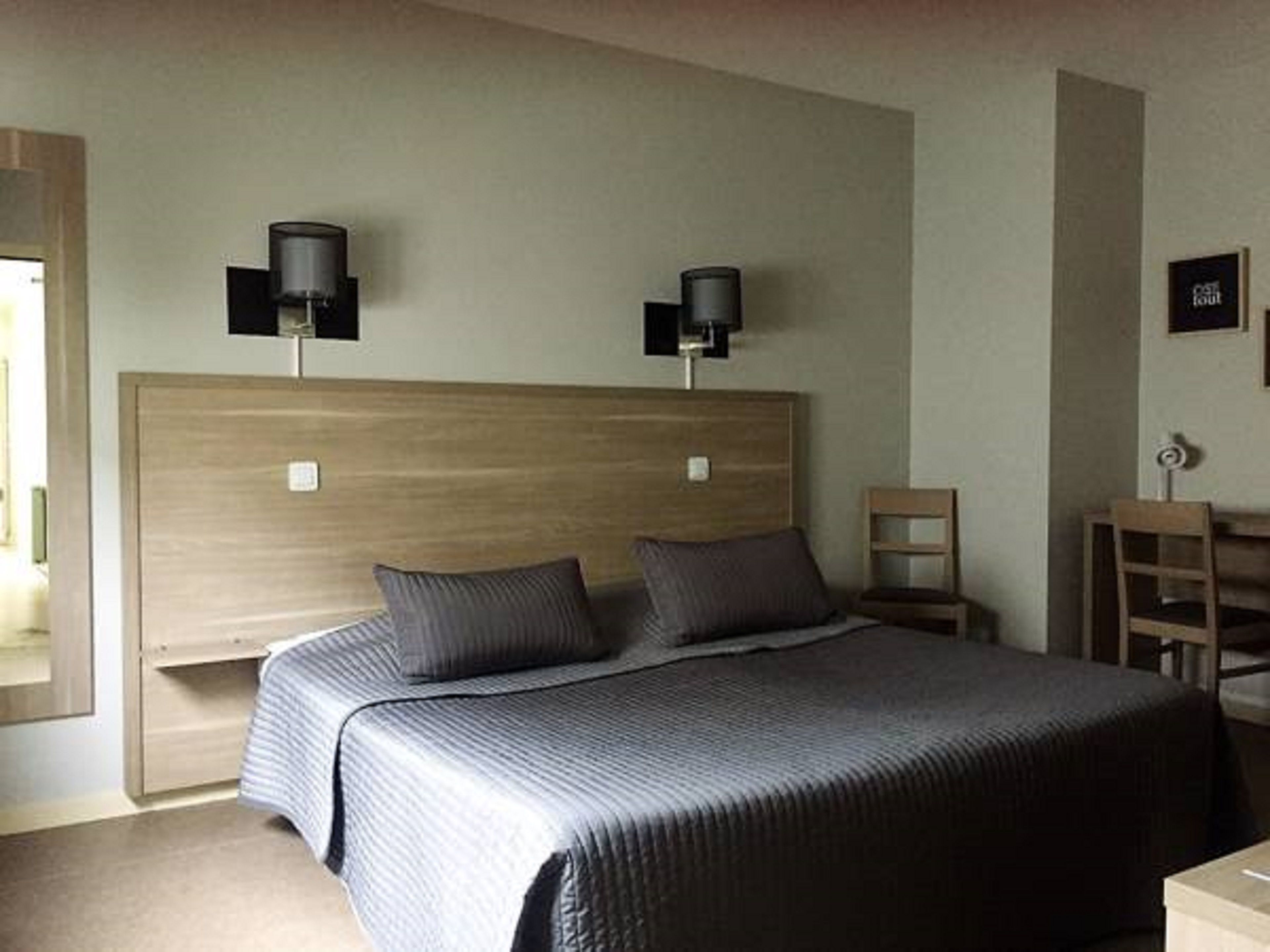 Un dormitorio con una cama grande, dos lámparas de noche, un cabecero de madera, un escritorio pequeño y una silla.