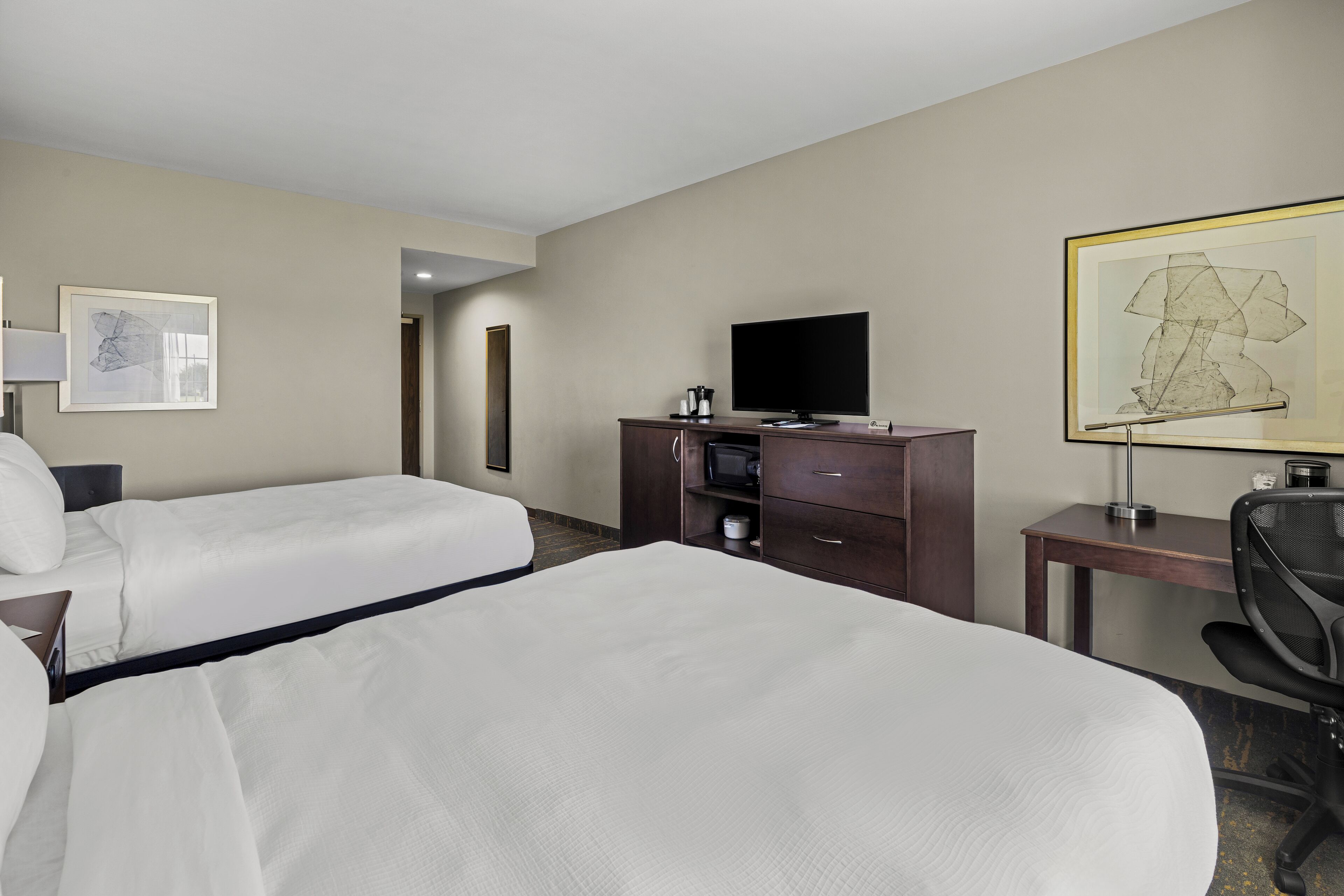 Habitación de hotel con dos camas, televisor, escritorio y silla.