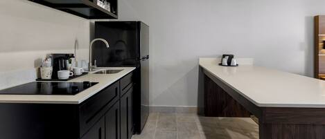 A modern kitchen with black cabinetry, a white countertop, and a built-in microwave.