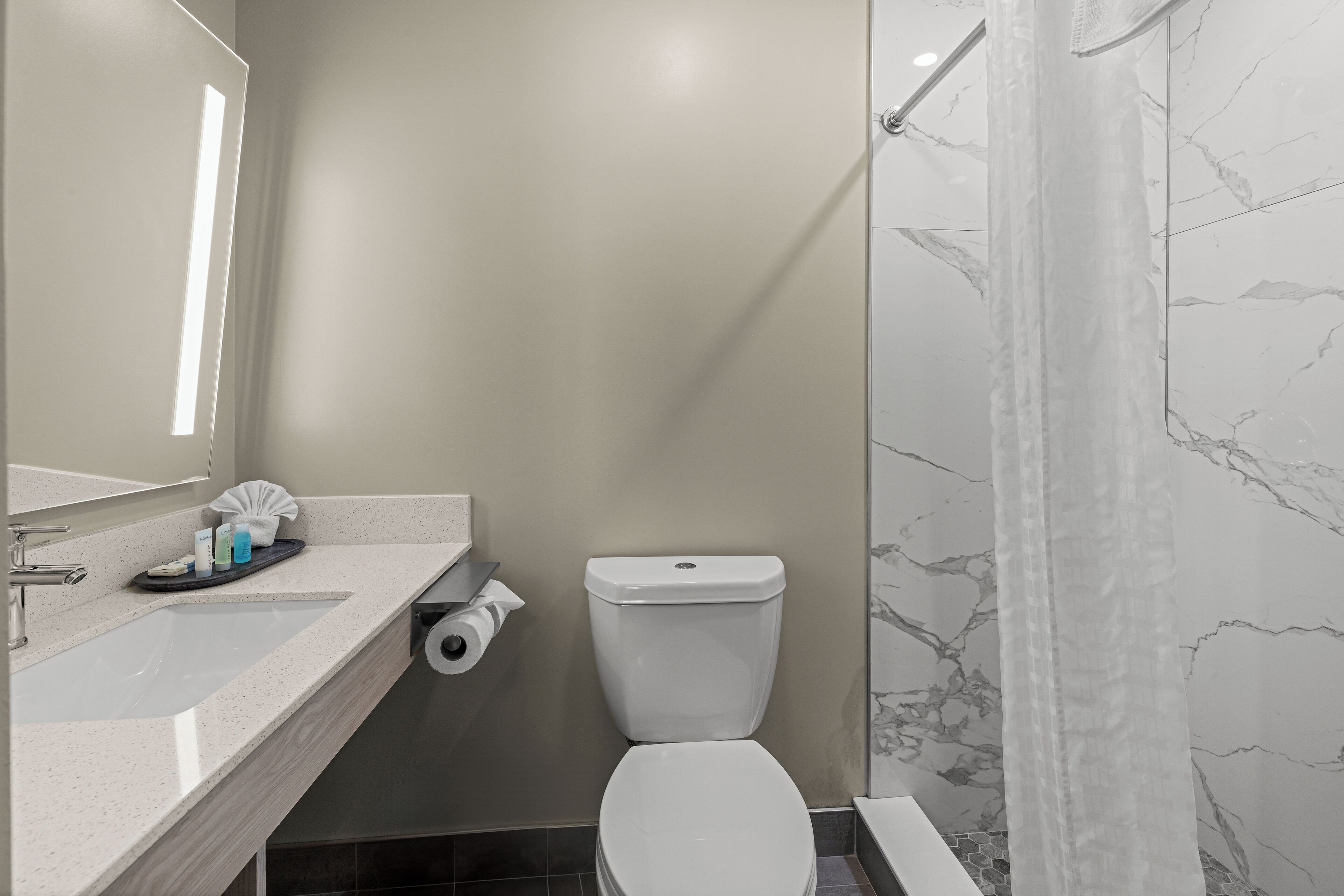 A modern bathroom with a white sink, toilet, and shower.