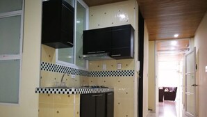 Una cocina con gabinetes negros, salpicadero de azulejos y techo de madera.