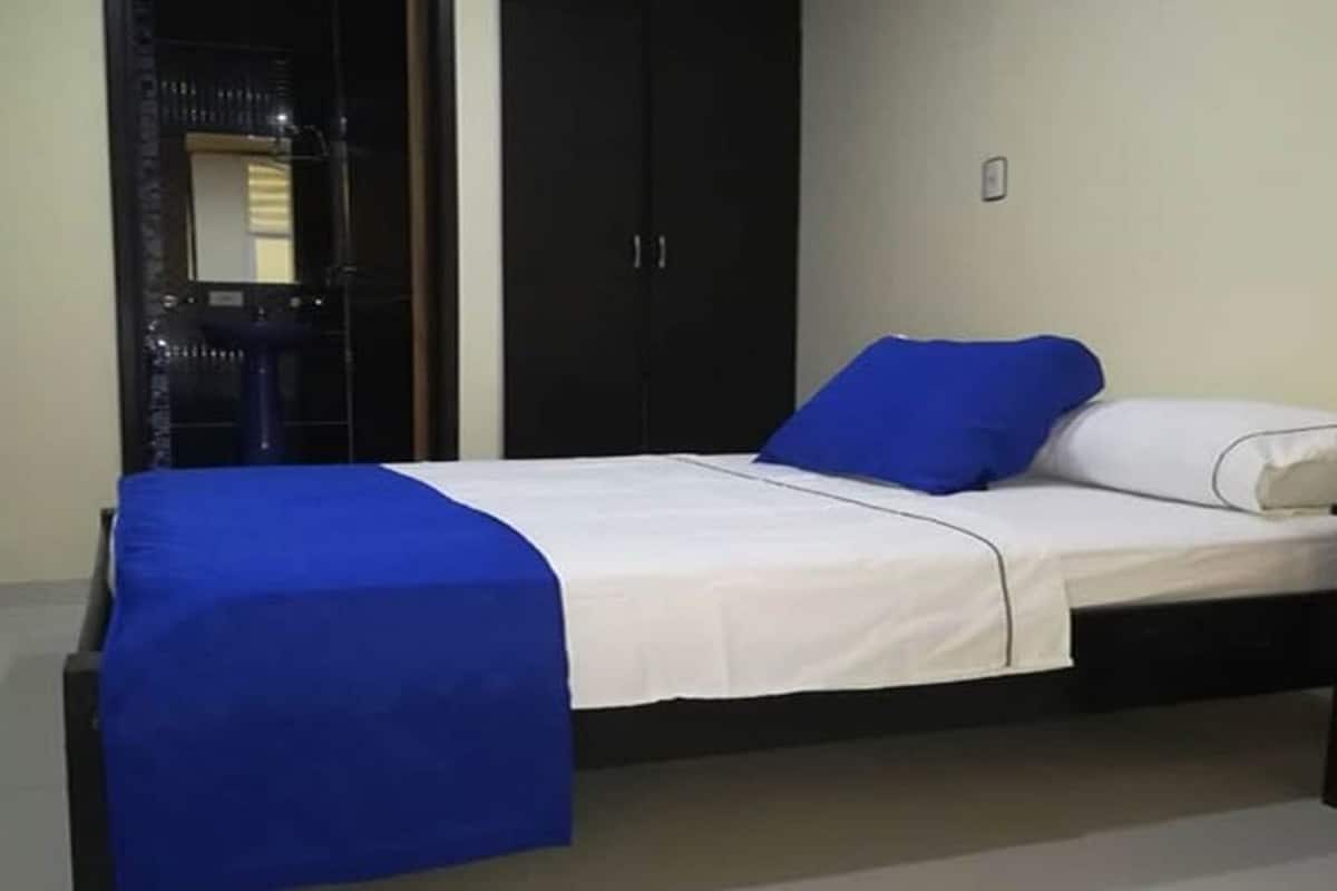A single bed with a blue and white bedspread, a black nightstand, and a wardrobe with a mirror.