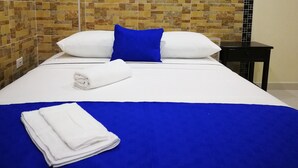 Una cama bien hecha con ropa de cama blanca y azul, una almohada azul y una toalla blanca doblada.