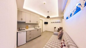 A compact living space with a kitchenette, a sofa, and a television. - Derin Apart Hotel Bodrum (Bodrum)