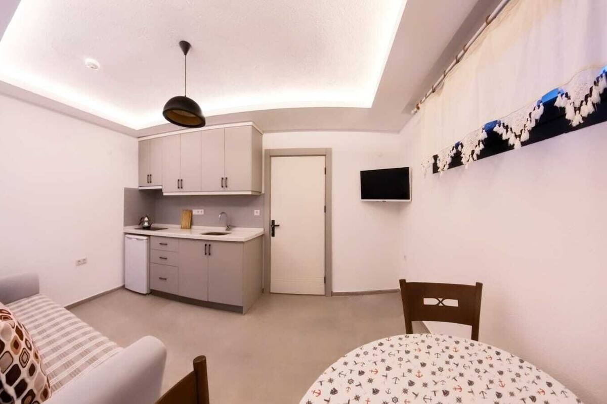 A compact living space with a kitchenette, a dining area, and a ceiling light fixture.