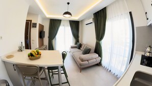 A modern living room with a sofa, dining table, and kitchen area. - Derin Apart Hotel Bodrum (Bodrum)