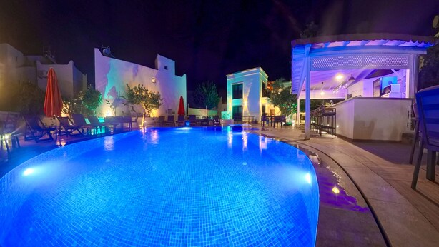 An outdoor swimming pool with a tiled surface, surrounded by lounge chairs and umbrellas. - Derin Apart Hotel Bodrum (Bodrum)